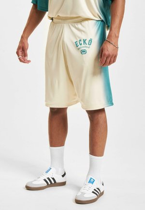 Cremefarvede og teal atletikshorts med elastisk talje, der har teksten "ECKŌ unlimited" og et logo på venstre ben. Glat stofstruktur.
