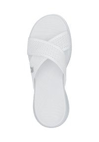 White slide sandal featuring an asymmetrical crisscross strap design with a mesh texture and a patterned footbed for grip.