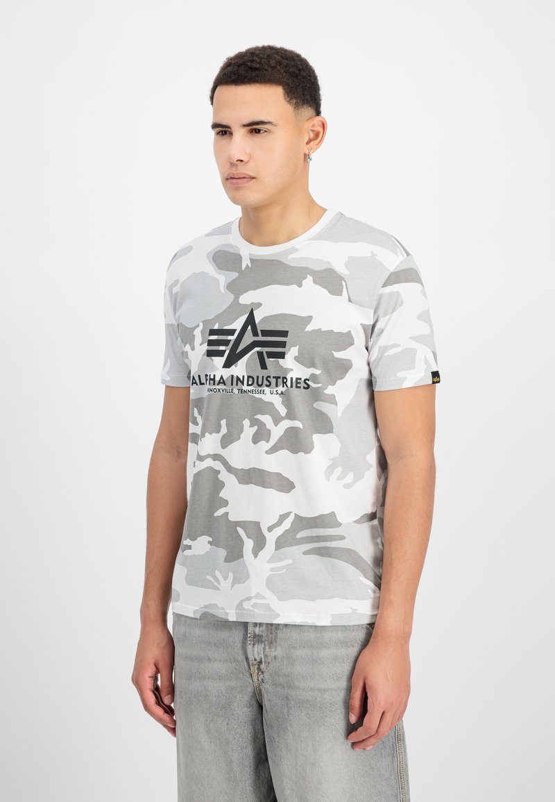 Γκρίζα μπλούζα κοντομάνικη με παραλλαγή, στρογγυλή λαιμόκοψη και λογότυπο "Alpha Industries" σε μαύρο χρώμα. Μαλακό βαμβακερό υλικό με ομαλή υφή.