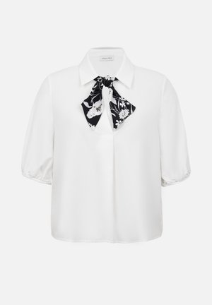 Blouse blanche à manches courtes avec un col pointu et un nœud papillon en cravate noire et blanche à motif floral au niveau de l'encolure.