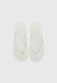 Weiße Flip-Flops aus Gummi mit einer strukturierten Fußbett und V-förmigen Riemen, die in der Mitte mit einem kleinen runden Akzent versehen sind.