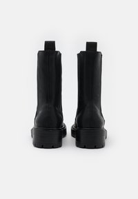 Czarne skórzane botki za kostkę o gładkim wykończeniu, z elastycznymi panelami bocznymi, wzmocnionym piętą i grubą bieżnikowaną podeszwą zapewniającą przyczepność.