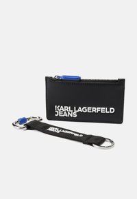 Čierny umelolepenkový kartuš s strieborným logom "KARL LAGERFELD JEANS", modrým zipsom, pripevneným čiernym popruhom a kovovou sponou.