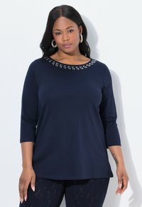 Marineblauw longsleeve shirt met een ronde halslijn, versierd met kleine zilveren details langs de kraag. Zacht, rekbaar materiaal. Casual pasvorm.