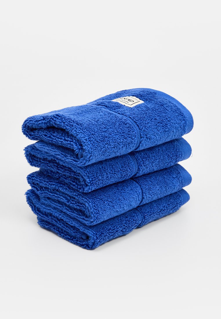 Zestaw czterech ułożonych w stos niebieskich ręczników wykonanych z teksturowanej tkaniny, z metką na górnym ręczniku. Każdy ręcznik jest starannie zwinięty.
