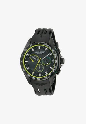Crni hronografski sat s teksturiranim crnim brojčanikom, zelenim akcentima i tahimetrom. Ima gumeni remen i Aston Martin logo.
