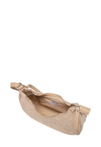 Beige kožená peněženka na zápěstí s embosovaným vzorem, nahoře na zip otevřená, ukazuje látkový vnitřek s kapsou na zip a štítkem uvnitř.
