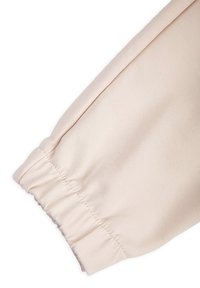 Jasnoróżowa tkanina o gładkiej fakturze i elastycznym mankiecie. Projekt posiada bufki w okolicy nadgarstka, co dodaje objętości.