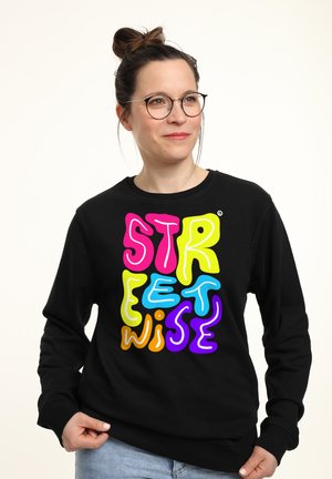 Zwarte sweatshirt met een kleurrijk, speels tekstontwerp dat "STREETWISE" in roze, geel, blauw, oranje en paars leest. Gemaakt van een katoenmix.