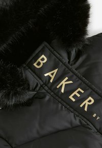 Crna puffer jakna s kapuljačom od umetničkog krzna; sadrži zlatni "BAKER" logo na tkaninskoj oznaci. Glatka tekstura s peglanom šavovima.