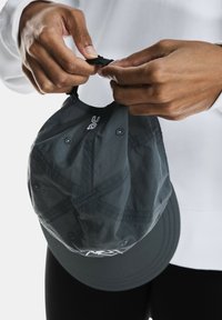 Căciulă gri cu o margine curbată și orificii de ventilație. Curea ajustabilă în spate, cu detalii de cusătură vizibile pe țesătură.