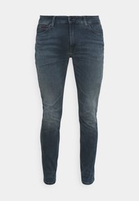 Mörkblå denimjeans med slim fit, med en lätt blekning, whiskeringdetaljer och ett litet hål på högra knäet. Femfickorsdesign.