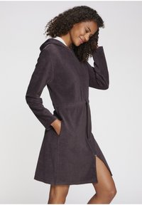 Kapuca, haljina za kupanje do gležnjeva u tamno sivoj ručničkoj tkanini. Ima duge rukave, bočne džepove i zatvaranje sa rajsferšlusom sprijeda.