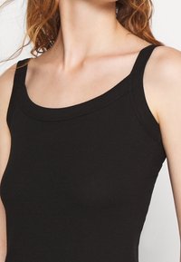 Czarny prążkowany top na ramiączkach z głębokim dekoltem i szerokimi paskami na ramiona, o gładkiej fakturze i dopasowanym kroju.