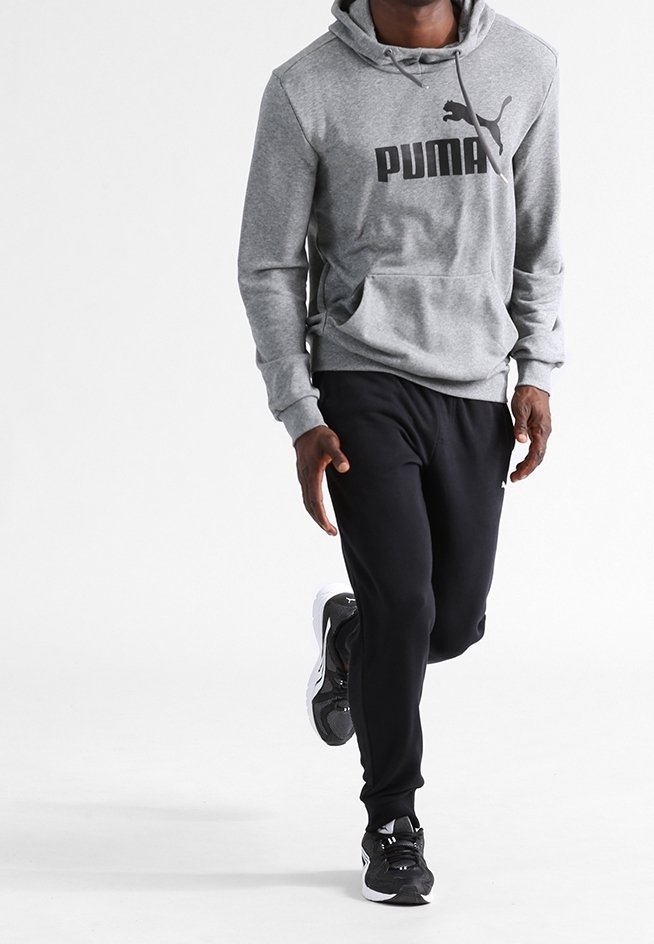 Šedá mikina s kapucí s velkým černým logem Puma, doplněná černými tepláky a černými sportovními botami, s volným střihem.