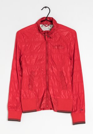 Rote leichte Jacke mit Reißverschluss, gerippten Bündchen und Saum, zwei Vordertaschen und hohem Kragen, an einem schwarzen Kleiderbügel hängend.