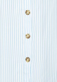 Ljusblå och vit randig skjorta med fem stora rundade knappar i marmorering, tillverkad av ett mjukt tyg.