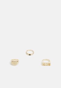 Conjunto de três anéis de ouro: um em forma de coração com detalhes em ponto, um anel fino com uma pedra preta e um anel robusto com números gravados.