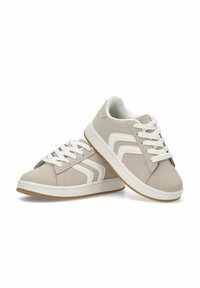 Zapatillas de tela gris con cordones blancos y tres rayas de acento a los lados. Presentan una suela de goma y un cuello acolchado suave.