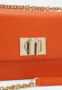 Oranžová texturovaná kožená kabelka se zlatým řetízkovým popruhem a obdélníkovým zlatým uzávěrem s vyrytým logem "Furla".
