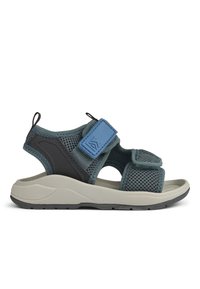 Tinkliniai sandalai tamsiai žaliu atspalviu su juodais akcentais ir mėlynu Velcro dirželiu. Yra tekstūruota pado danga ir šviesiai pilka padas su sukibimo dizainu.