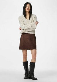 Light beige knitted cardigan with lace sleeves, paired with a brown suede mini skirt and knee-high black leather boots.