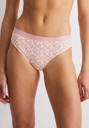 Slip di cotone rosa con motivo floreale bianco, cintura elastica con nome del marchio in rilievo e design a bikini. Texture liscia.