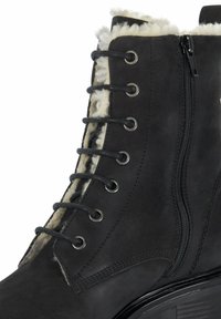 Zwarte leren enkelboot met nepbontvoering, metalen veterogen en een zijrits voor gemakkelijke aantrekking. Heeft een getextureerde rubberen zool.