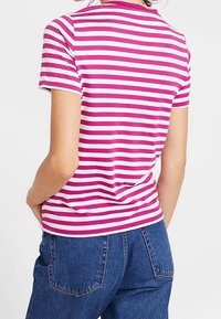 Camiseta de manga corta con rayas horizontales rosas y blancas, cuello redondo y forma ajustada, combinada con jeans de denim de cintura alta.