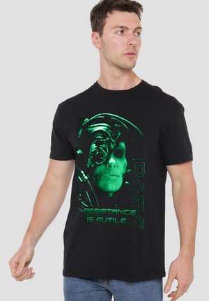 Black cotton t-shirt featuring a green graphic print of a face with a helmet and pipes, and text reading "RESISTANCE IS FUTILE."
