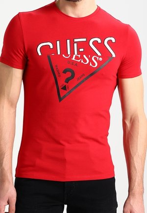 T-shirt en coton rouge avec un grand logo graphique noir et blanc en forme triangulaire. Manches courtes et encolure ronde.