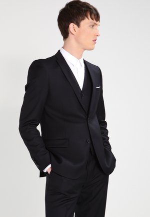 Black tailored suit with a fitted waistcoat, white shirt underneath, and a single pocket square. Smooth fabric with structured design.