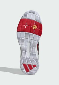 Sål med en struktureret hvid gummibase, en rød midtersektion med en gul cirkulær detalje og et sort stribet design på siden.