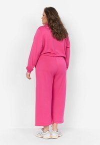 Completo sportivo fucsia composto da due pezzi, con felpa comoda e pantaloni a gamba larga, realizzato in tessuto morbido, con polsini e vita a coste.