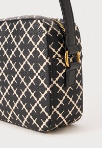 Juodas ir kreminis raštuotas per kūną nešiojamas krepšys su tekstūruota paviršiumi, auksine užtrauktuku ir tvirtu juodu diržu. Kompaktiška stačiakampė forma.