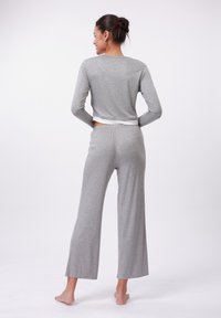 Ensemble de haut à manches longues gris et de pantalons à jambe large, fabriqué en tissu doux, présentant une coupe décontractée avec une légère ceinture et sans motifs visibles.