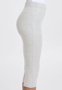 Leggings en mélange de coton gris clair avec une texture côtelée, taille haute et longueur cropped, présentant des coutures latérales et sans matériel visible.