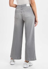 Gray wide-leg jeans shown from the back, featuring two rear pockets and a mid-rise waistband. Textured fabric with subtle stitching details.