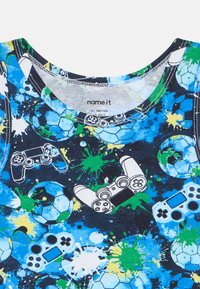 Modré bavlněné tričko s kulatým výstřihem, se skvrnitým vzorem zelené a modré barvy, a grafikami fotbalových míčů a herních ovladačů.