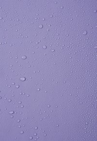 Μοβ φόντο με πολυάριθμες σταγόνες νερού, διαφόρων μεγεθών και σχημάτων, δημιουργώντας μια υφή με γυαλιστερή εμφάνιση.