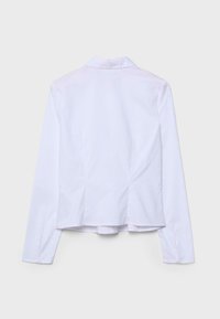 Blouse blanche à manches longues pour femme avec col, boutons aux poignets et coutures ajustées, vue de dos sur un fond uni.