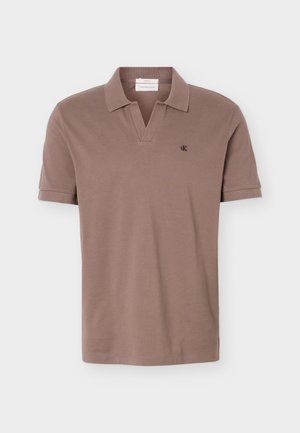 Brun kortærmet polo med åben krave og lille sort "ck" logo på venstre bryst mod en ensfarvet baggrund.