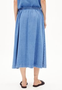 Denim long skirt with an elastic waistband, featuring a light blue color, flowing shape, and subtle stitching detail at the hem.