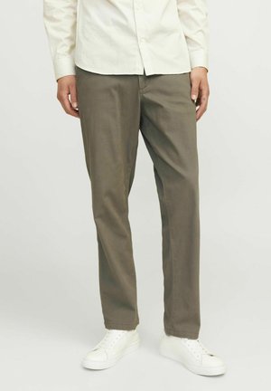 Pantalones caqui de algodón, con un diseño de pierna recta y una textura suave, combinados con zapatillas blancas.