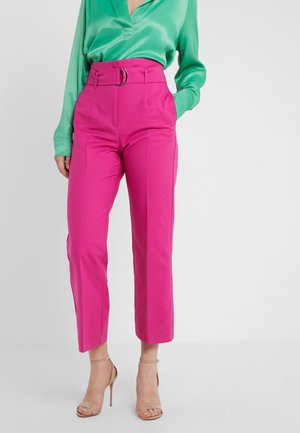 Felle roze hoge taille broek met een brede pijp, voorzien van een voorste riemgesp en plooien, gecombineerd met een groen satijnen blouse met lange mouwen.