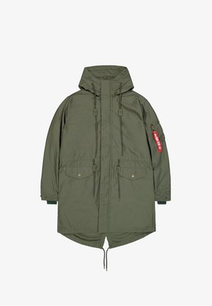 Oliwkowa parka z kapturem, z zamkiem błyskawicznym z przodu, sznurkami ściągającymi, kieszeniami na klapę oraz czerwoną metką „Remove Before Flight” na kieszeni lewego rękawa.