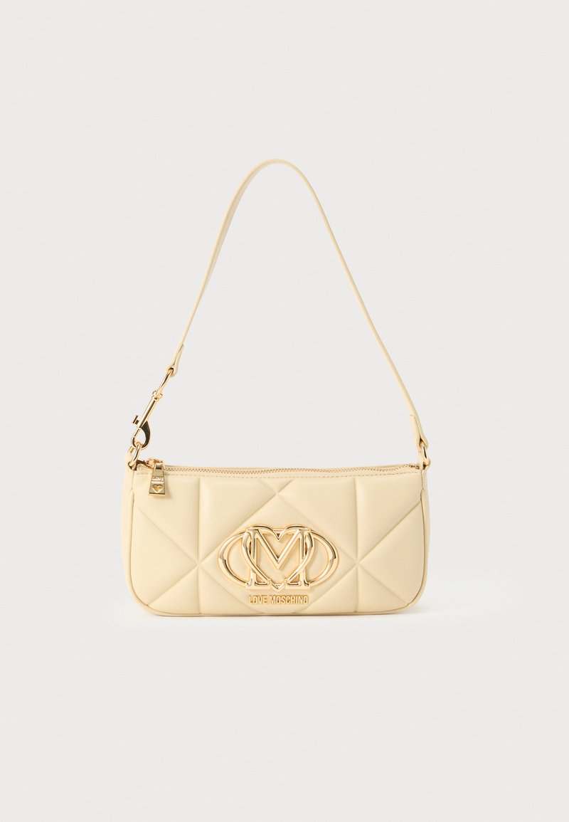 Κρεμ τσάντα χειρός με ραφές, με χρυσά μεταλλικά στοιχεία, που διαθέτει εμφανές λογότυπο και έναν μόνο ιμάντα ώμου. Λείο υλικό, ορθογώνιο σχήμα.