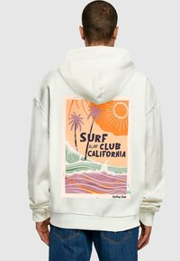 Light beige hoodie featuring a large graphic on the back with palm trees, waves, sun, and text "SURF CLUB CALIFORNIA" in bold font.
