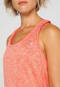 Rosa heathered träningstopp i andningsbart material. Har breda axelremmar och en liten metallisk logotyp på bröstområdet.