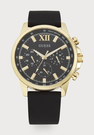 Black chronograph watch with a gold-tone case, featuring a black dial, white hour markers, and a rubber strap. Notable tachymeter scale present.